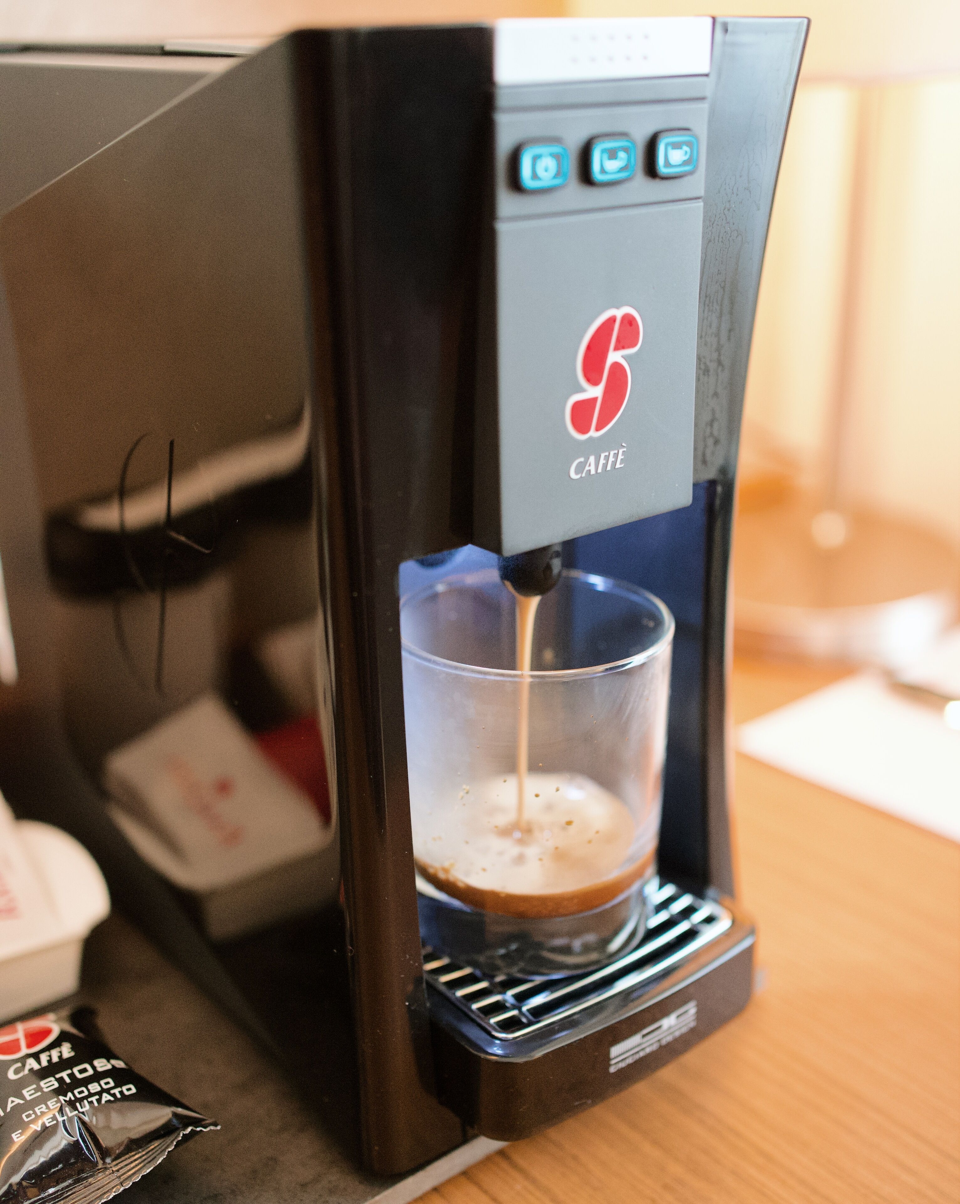 A coffee machine dispensing coffee into a clear glass cup.