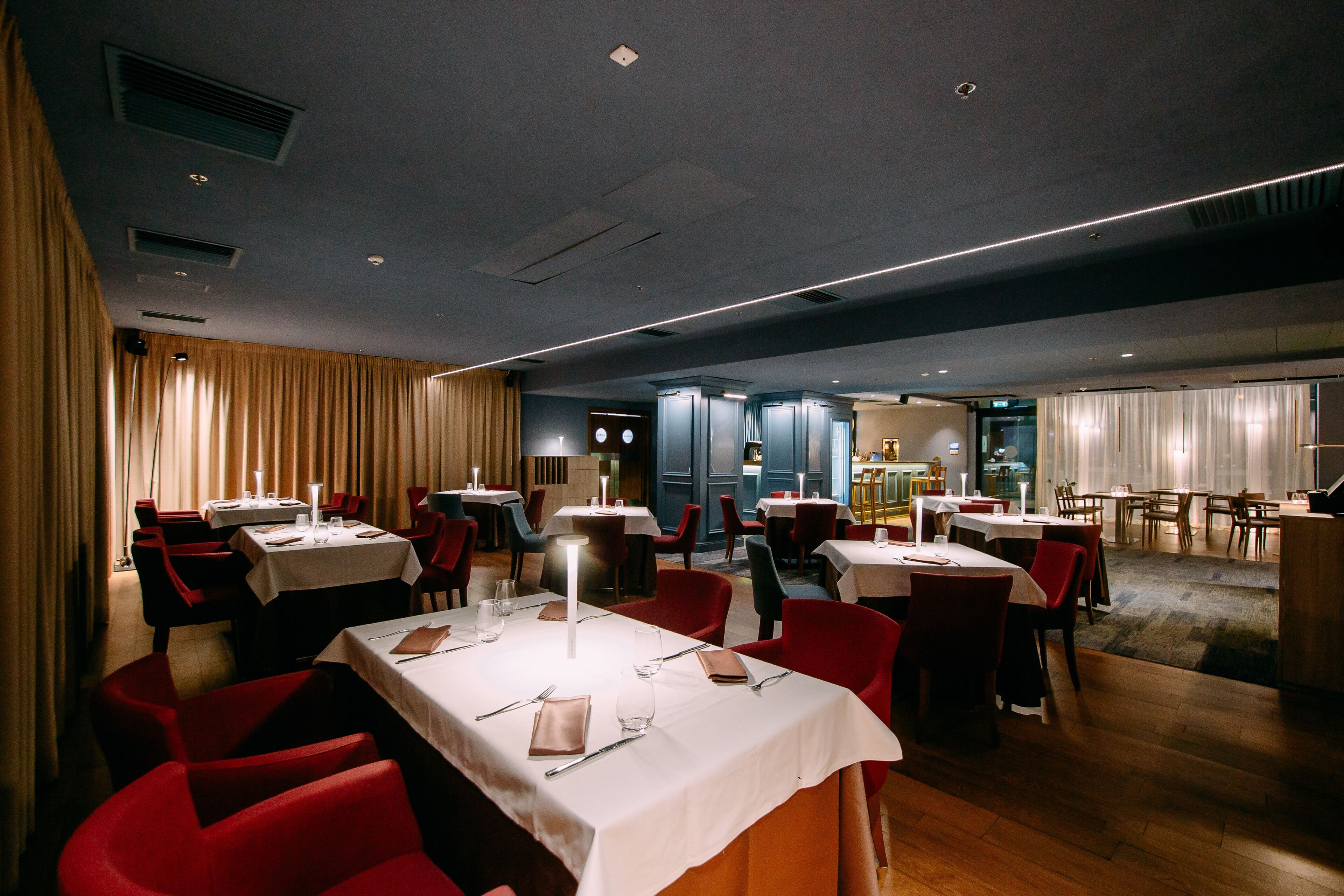 A restaurant with multiple tables and chairs, some with candles.