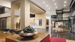 A spacious lobby with a central seating area, a large decorative bowl, and a staircase. - Ramada by Wyndham Oradea (Oradea)