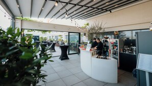 A modern outdoor café with a curved counter, tables, and a vending machine. - Ramada by Wyndham Oradea (Oradea)