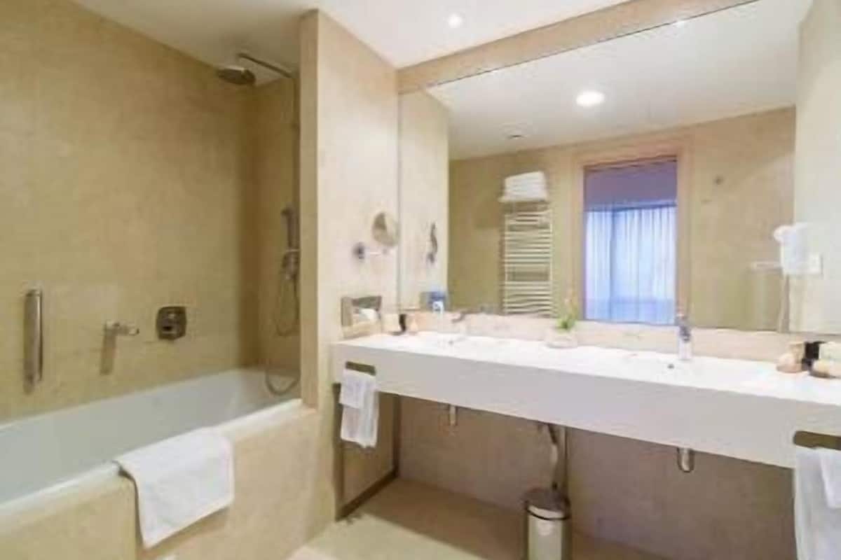 luxury suite, 1 king bed, non smoking | bathroom | eco-friendly toiletries, hair dryer, slippers, towels