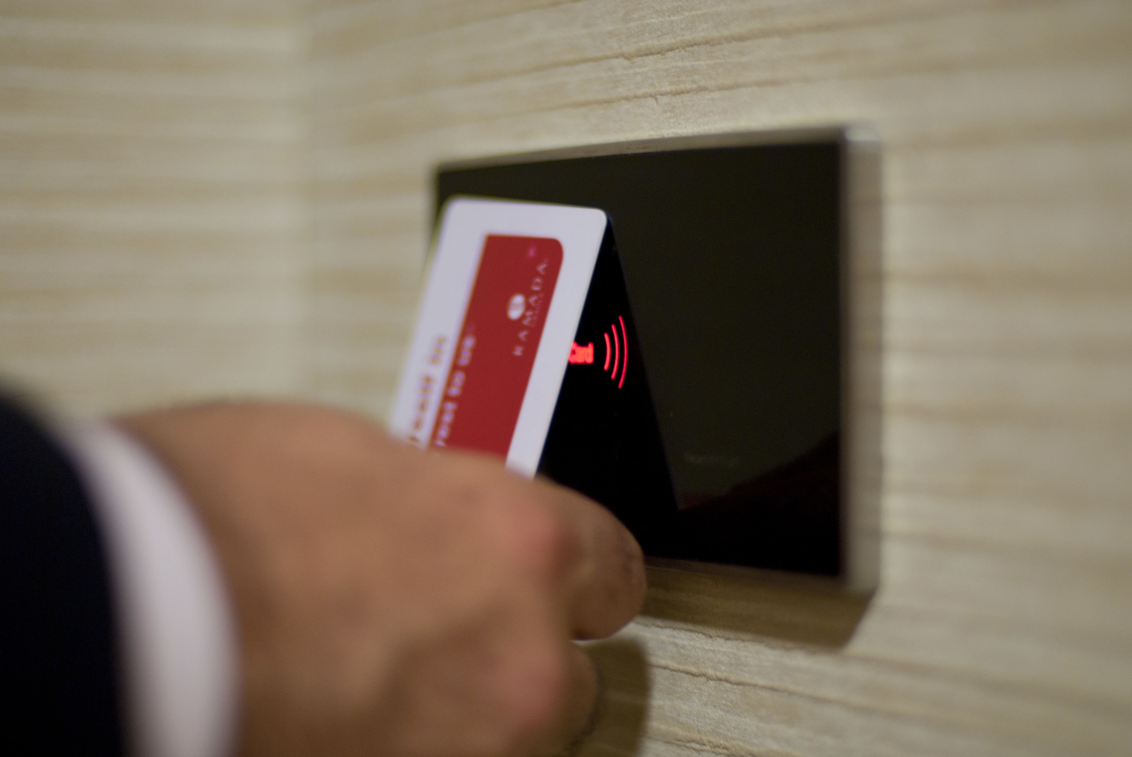 A hand inserting a card into a slot with a red signal indicating a card reader.