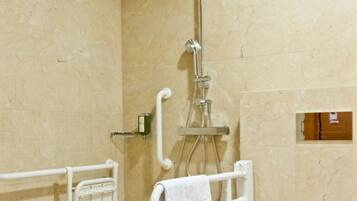 A modern bathroom with a shower, toilet, and handrails.