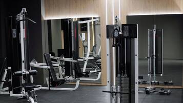 A modern gym with various exercise machines, a mirror, and a wooden accent wall.