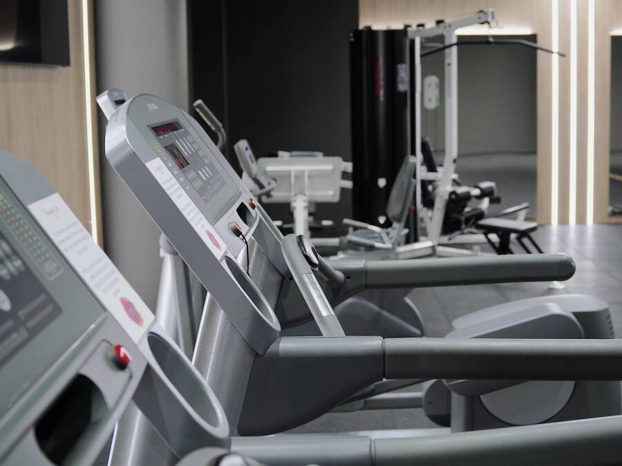 Varias bicicletas estáticas alineadas en un gimnasio, cada una con pantalla digital y panel de control.