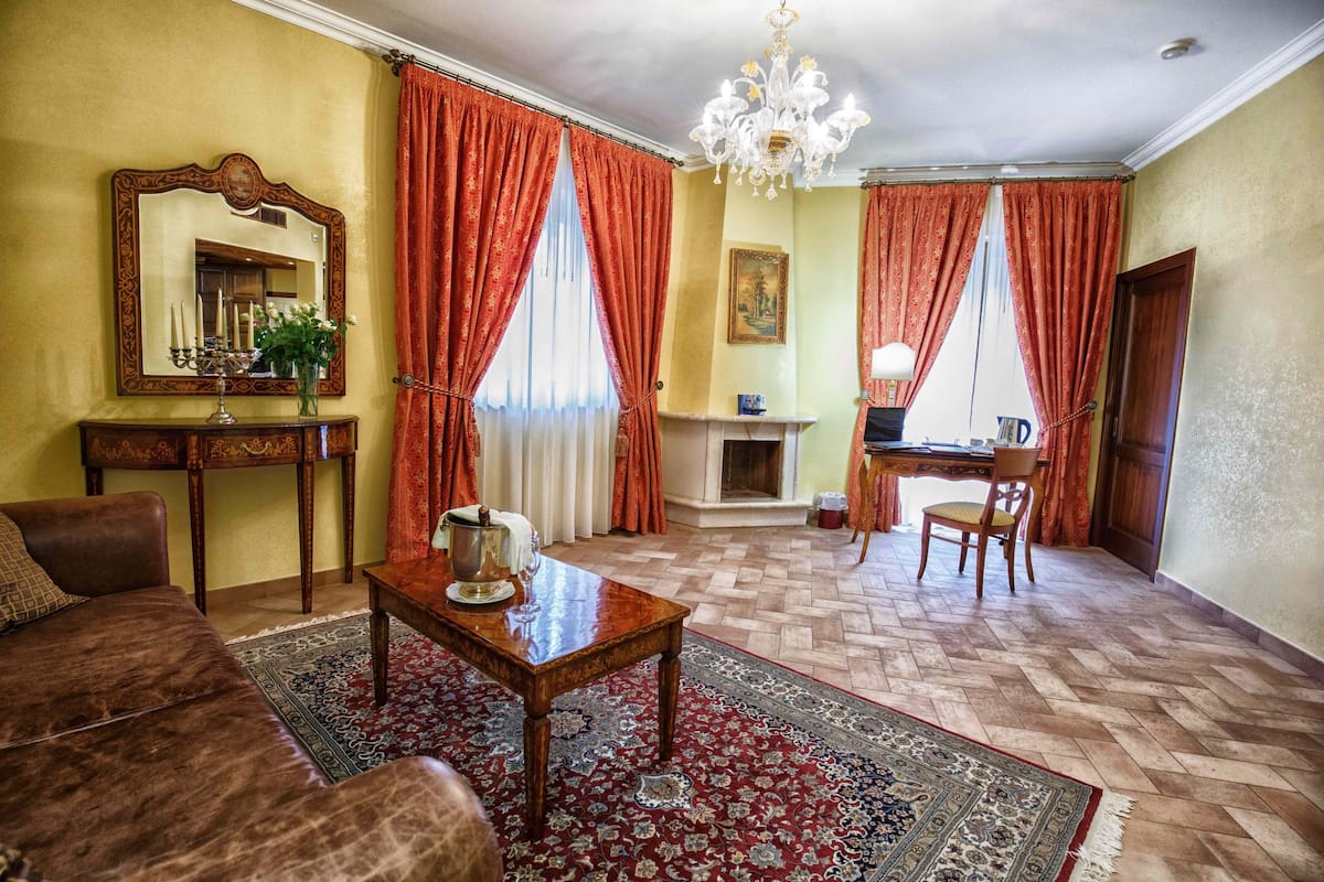 A traditional living room with a fireplace, a chandelier, and a large mirror.