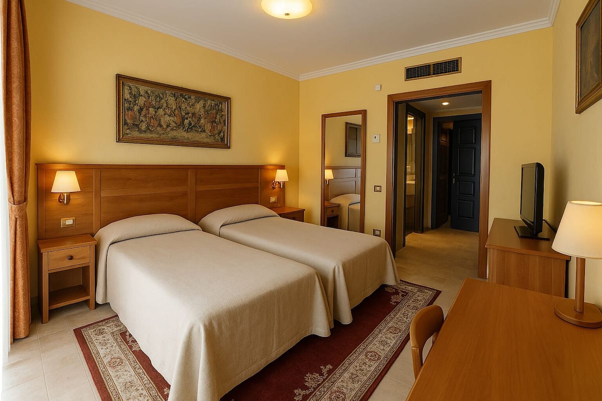 A hotel room with two beds, a desk, a television, and a painting on the wall.