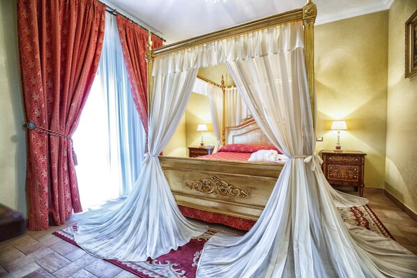 A four-poster bed with a canopy, a nightstand with a lamp, and a red and white patterned rug. - Grand Hotel Vigna Nocelli (Lucera)