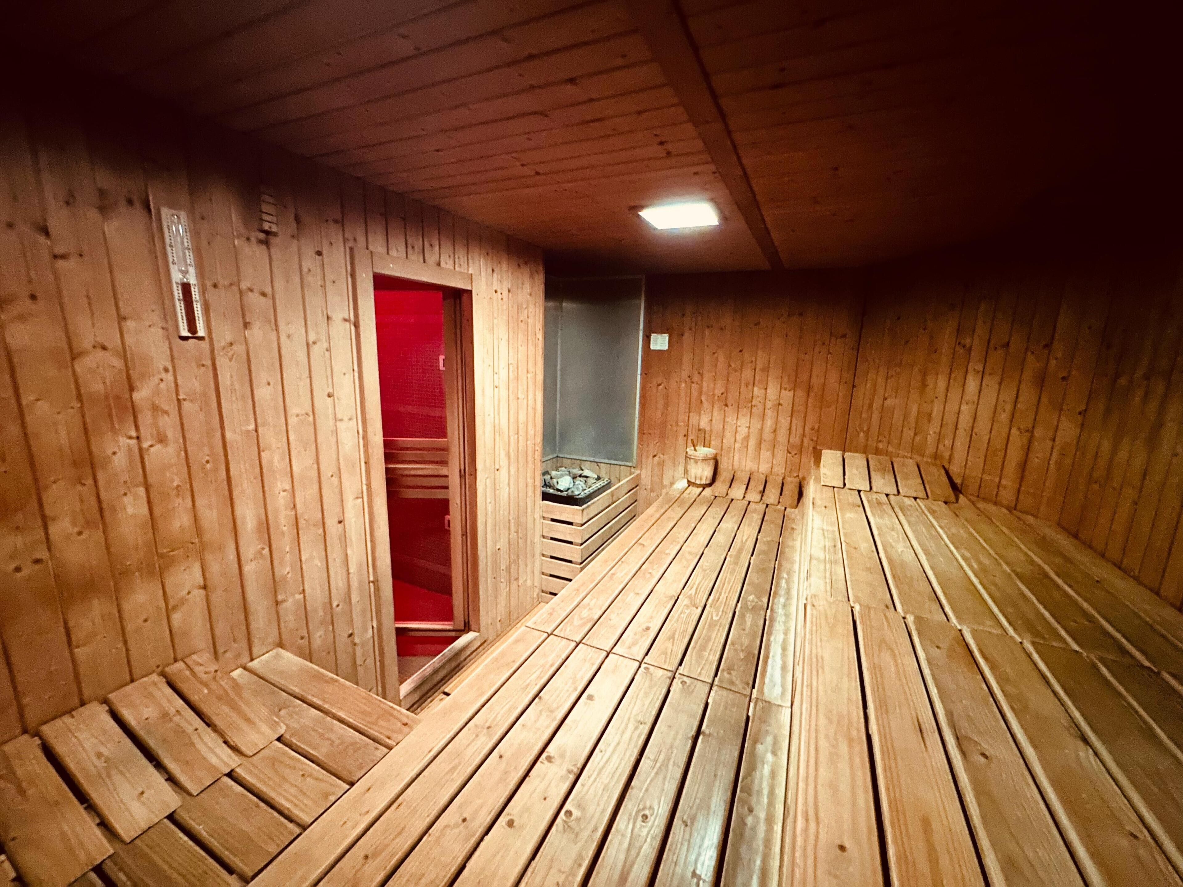 Eine Sauna mit Holzbänken und einer roten Tür.