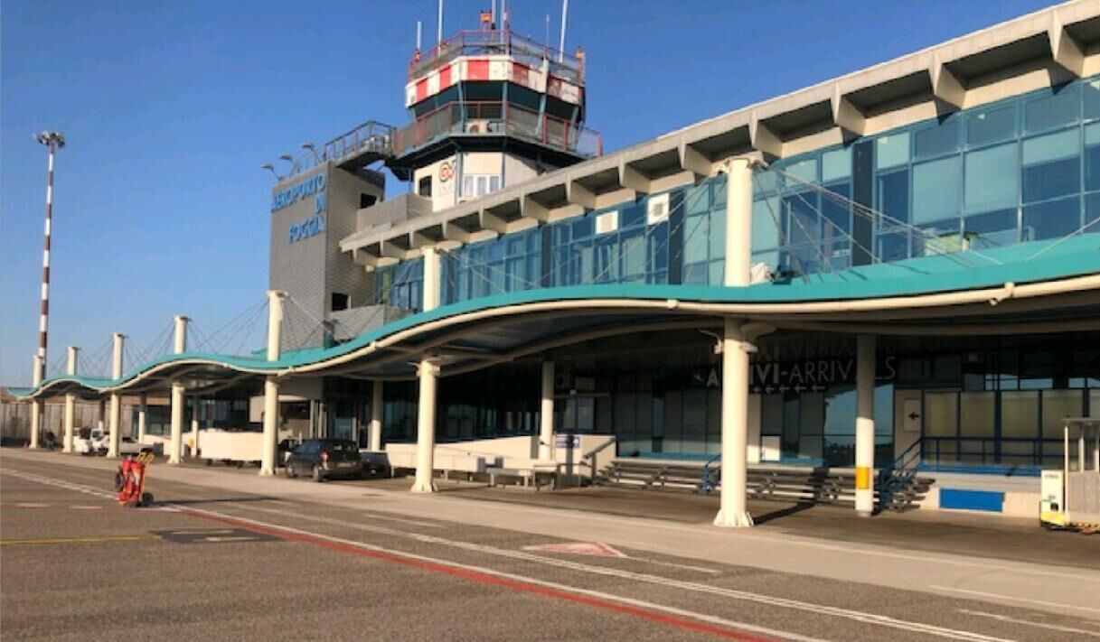 Ein Flughafen-Terminal mit modernem Design, ausgestattet mit einer großen Glasfassade und einem Kontrollturm im Hintergrund.
