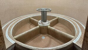 A circular hot tub with a central column and four seating areas, surrounded by a tiled wall. - Grand Hotel Vigna Nocelli (Lucera)