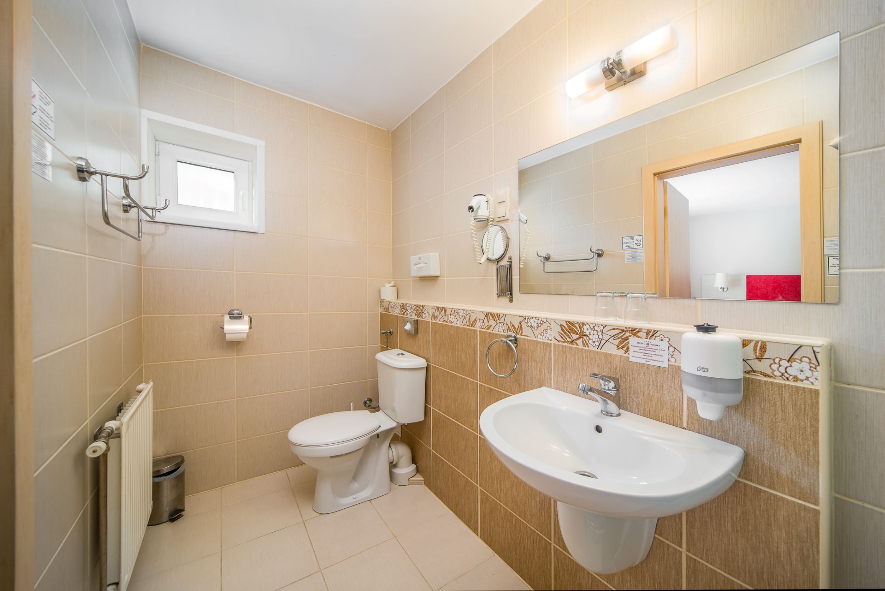 A modern bathroom with a toilet, bidet, sink, and a mirror.