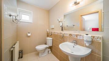 A modern bathroom with a toilet, bidet, sink, and a mirror.