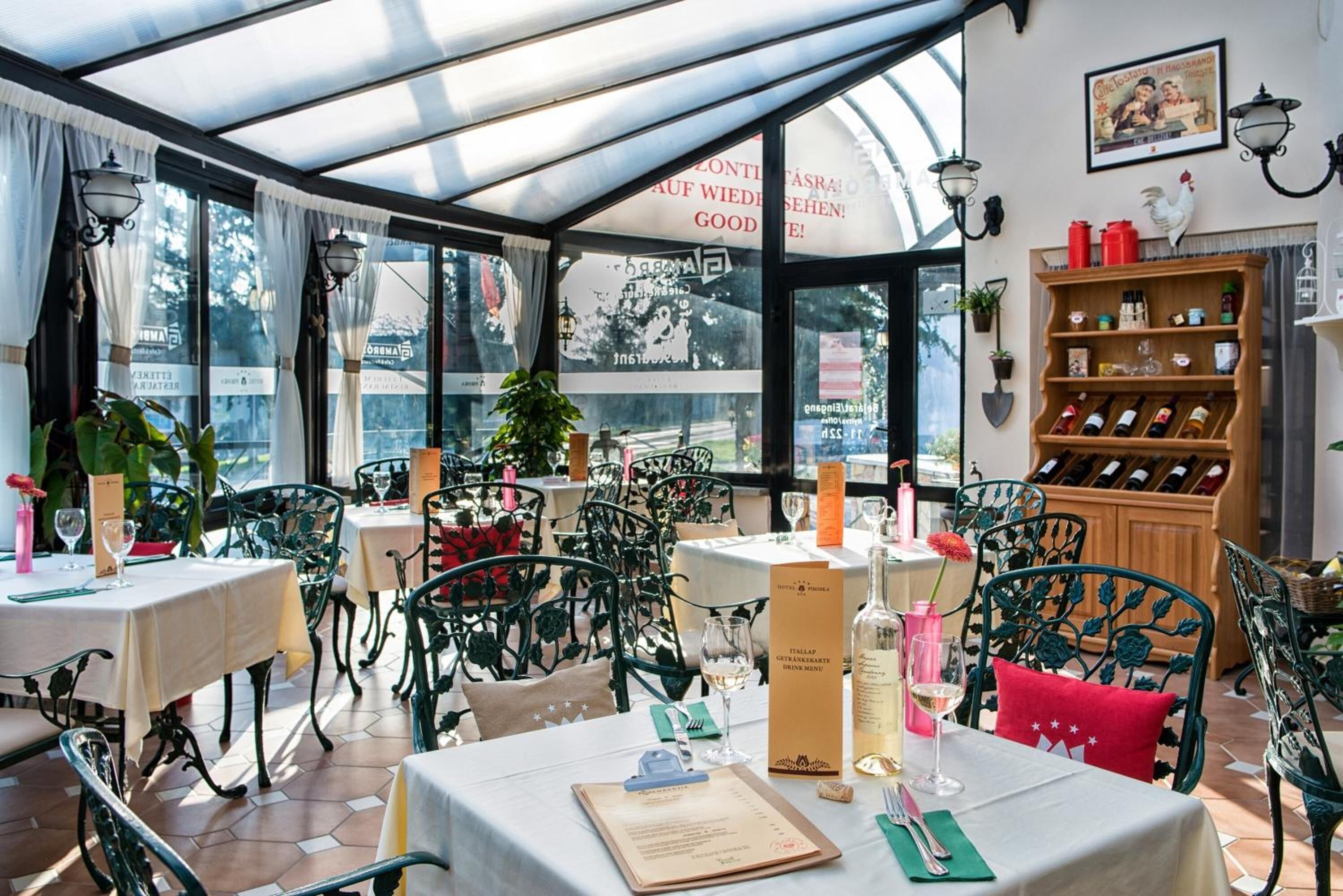 A restaurant with outdoor seating, tables with menus, and a wine rack.