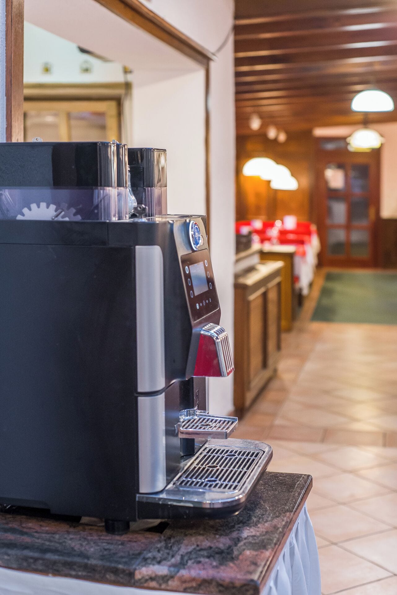A coffee machine with a digital display, a water reservoir, and a drip tray on a marble countertop.