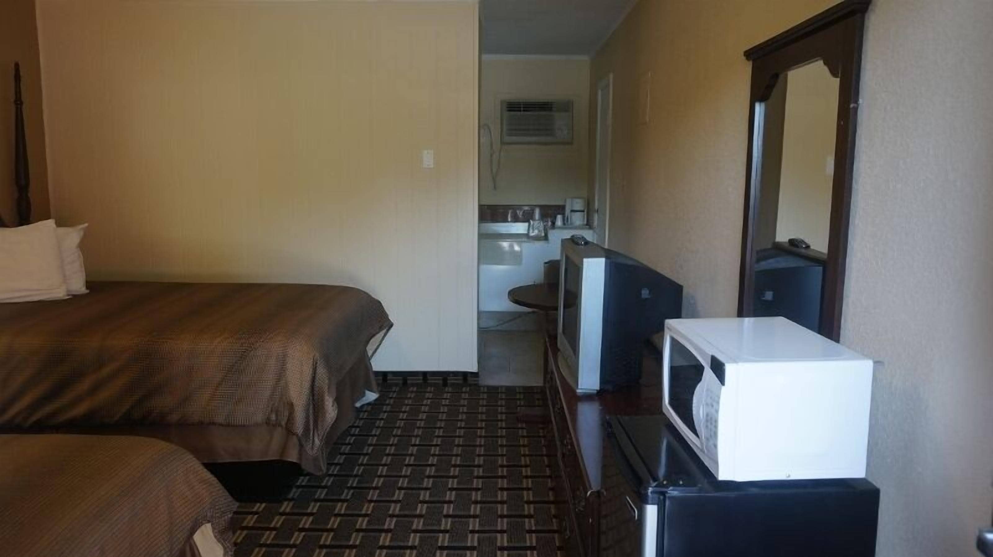 A hotel room with a bed, a television, a microwave, and a small kitchenette area.