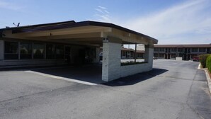 A building with a covered entrance, a brick pillar, and a parking lot. - Budget Inn Malvern (Malvern)
