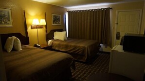 A hotel room with two beds, a desk, a lamp, a television, and a door. - Budget Inn Malvern (Malvern)