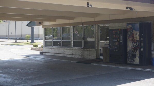 A building with a brick facade, large windows, and a vending machine on the right.