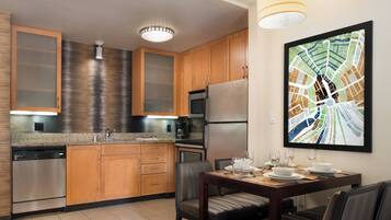 A modern kitchen with wooden cabinets, stainless steel appliances, and a dining area with a table set for four.