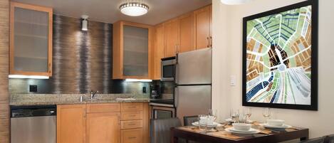 A modern kitchen with wooden cabinets, stainless steel appliances, and a dining area with a table set for four.