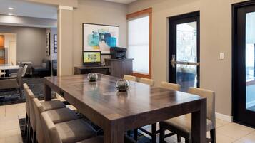 A modern dining area with a wooden table, cushioned chairs, and a projector screen.