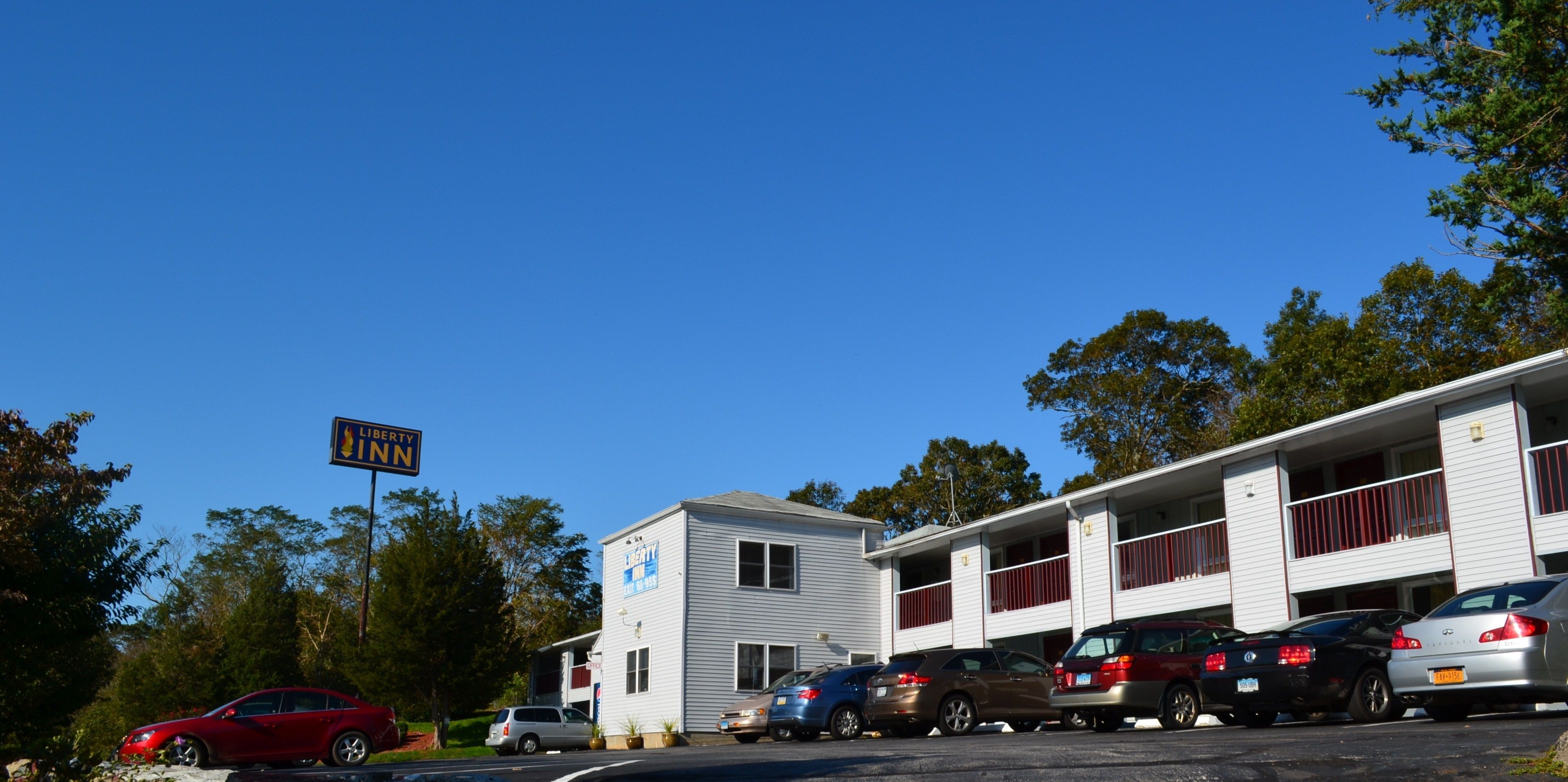 A motel with a sign reading "Liberty Inn" and a parking lot with several cars.