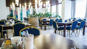 A restaurant with multiple tables and chairs, some with plants and decorative items. - Hotel Liberec (Liberec)