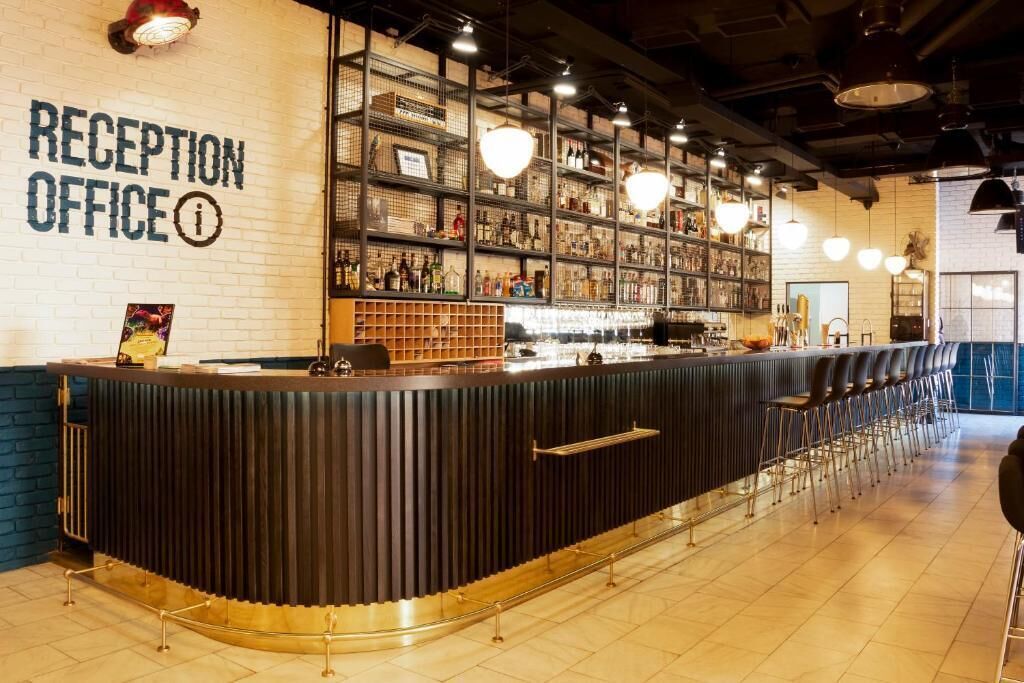 A reception area with a counter, shelves with various items, and a bar area with stools.