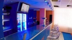 A bar area with a counter labeled "Hotel Library," bar stools, and a television screen above the counter. - Hotel Liberec (Liberec)