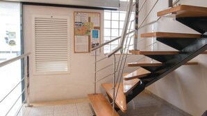Una escalera moderna con peldaños de madera y barandillas de metal, que sube a un piso superior.