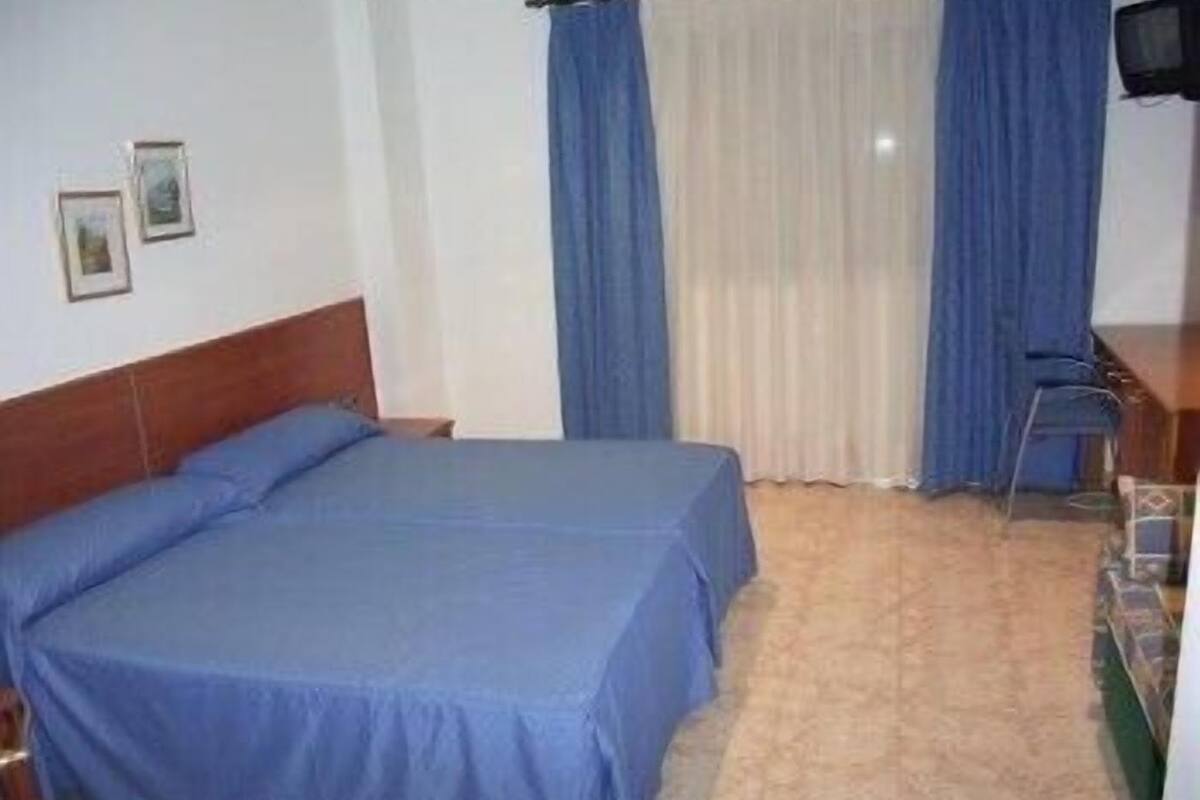 A hotel room with a bed, a desk, and a television.