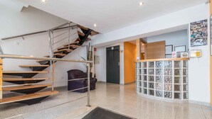 Un interior moderno con una escalera, un mostrador de recepción y una pared con cuadros enmarcados.