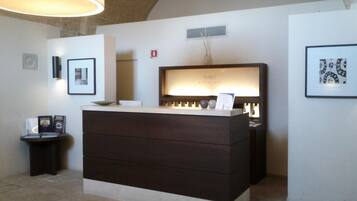 A reception desk with a dark wooden finish, a framed picture above it, and a wall-mounted vent.