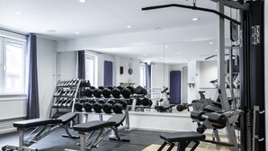 A gym with weightlifting equipment, benches, and dumbbells. - Fågelbro Säteri (Fågelbrolandet)