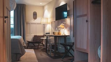 A hotel room with a bed, a desk, a chair, a television, and a wardrobe.