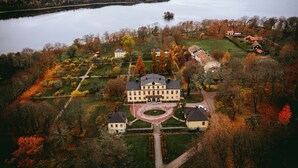 Un vaste domaine comprenant un bâtiment principal, plusieurs constructions plus petites et un lac en arrière-plan.