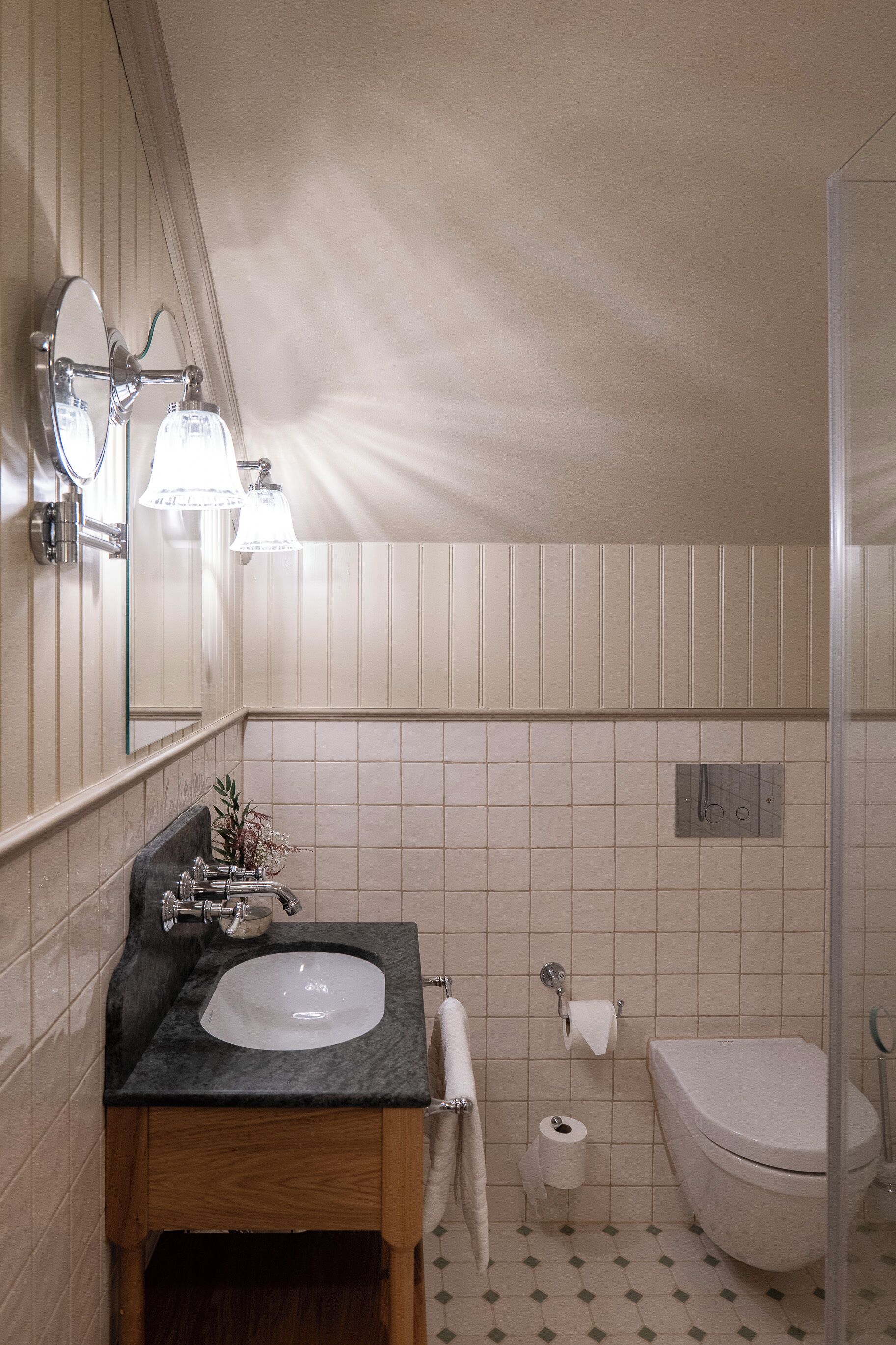 A bathroom with a sink, mirror, towel rack, toilet, and shower.