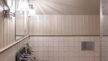 A bathroom with a sink, mirror, towel rack, toilet, and shower.