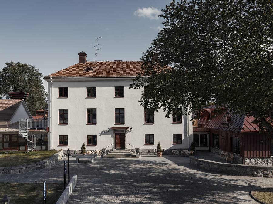 A large, white building with a red-tiled roof, multiple windows, and a central entrance.