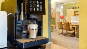 Una cafetera con pantalla digital y una taza de café.