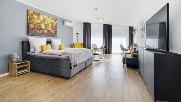 Una habitación de hotel moderna con cama, escritorio y televisor.