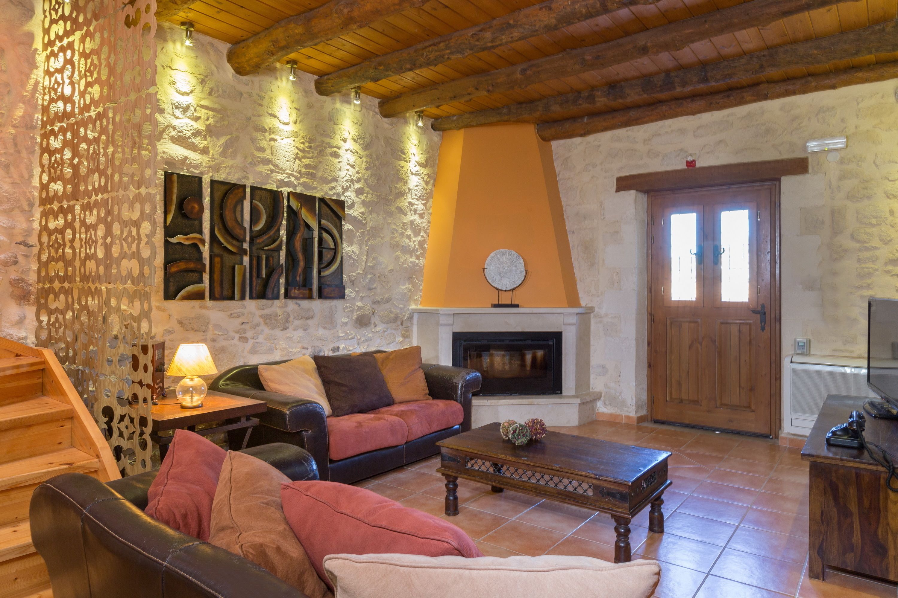 A cozy living room with a fireplace, a sofa, a coffee table, and a TV.