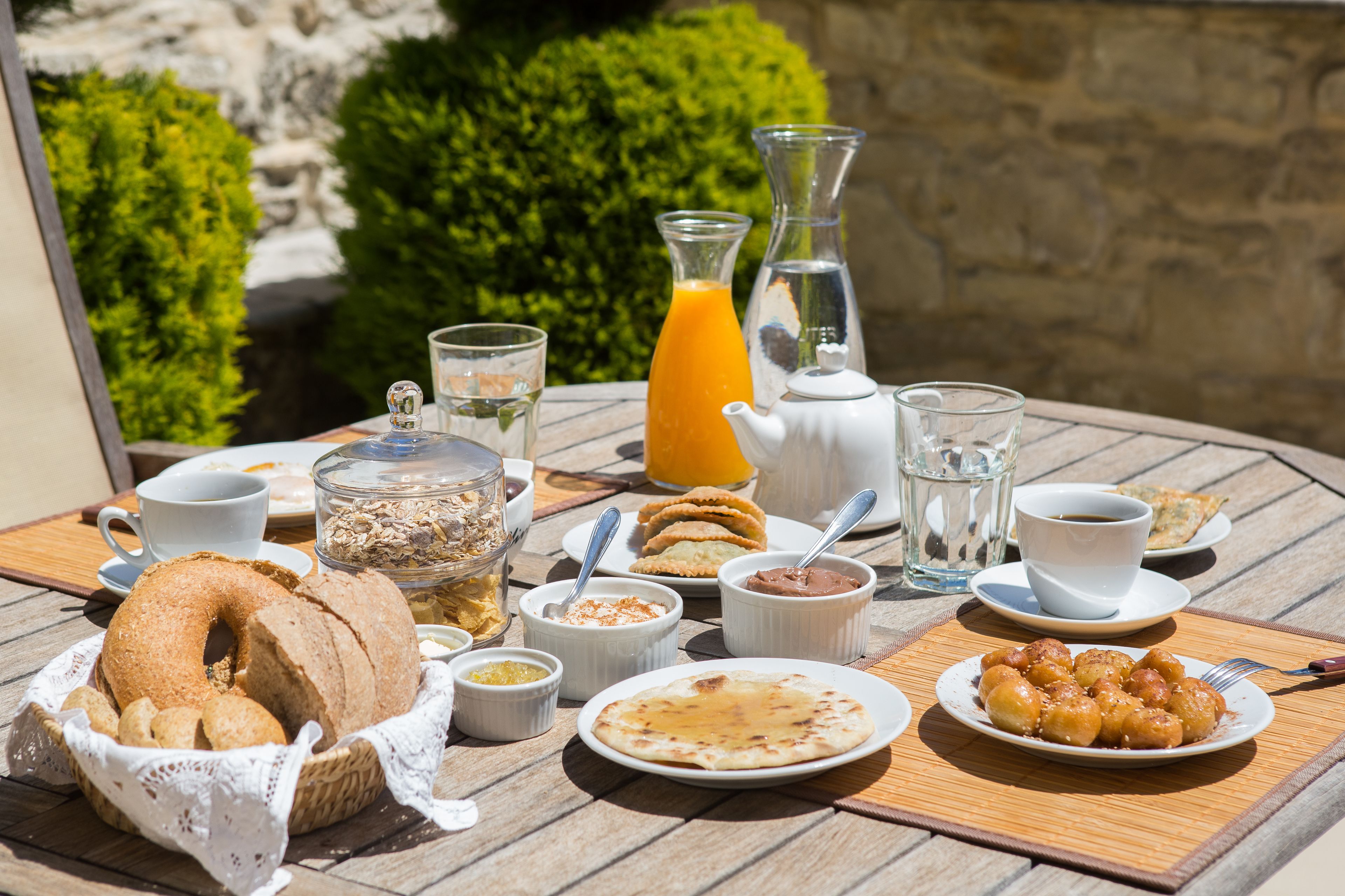 A breakfast table with various food items, including pastries, a jug of orange juice, and a teapot.