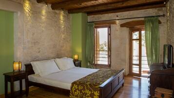 Un dormitorio con cama de madera, paredes de piedra, una puerta verde y un aparador de madera.