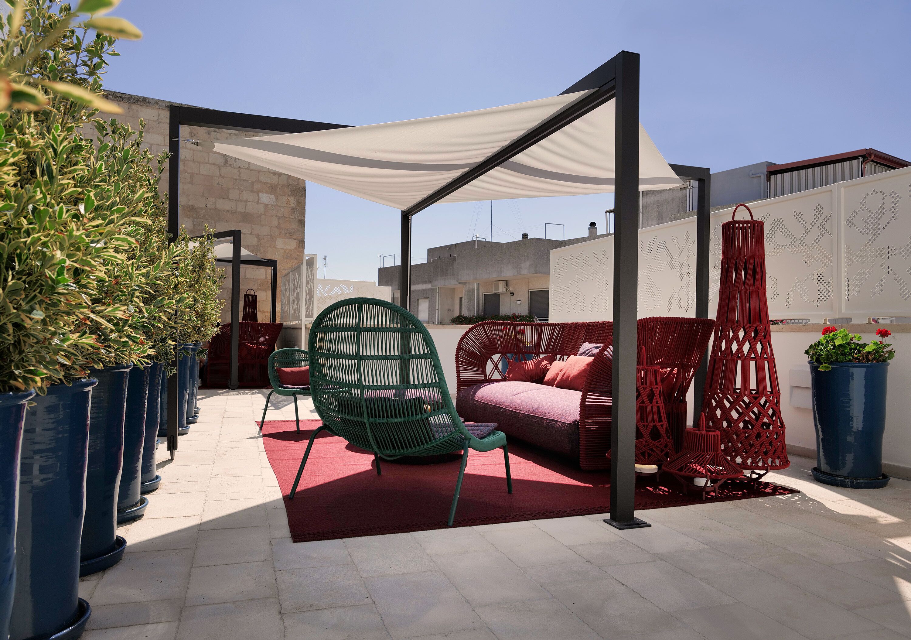 En tagterrasse med udendørs siddepladser, plantekasser og et hvidt markise.