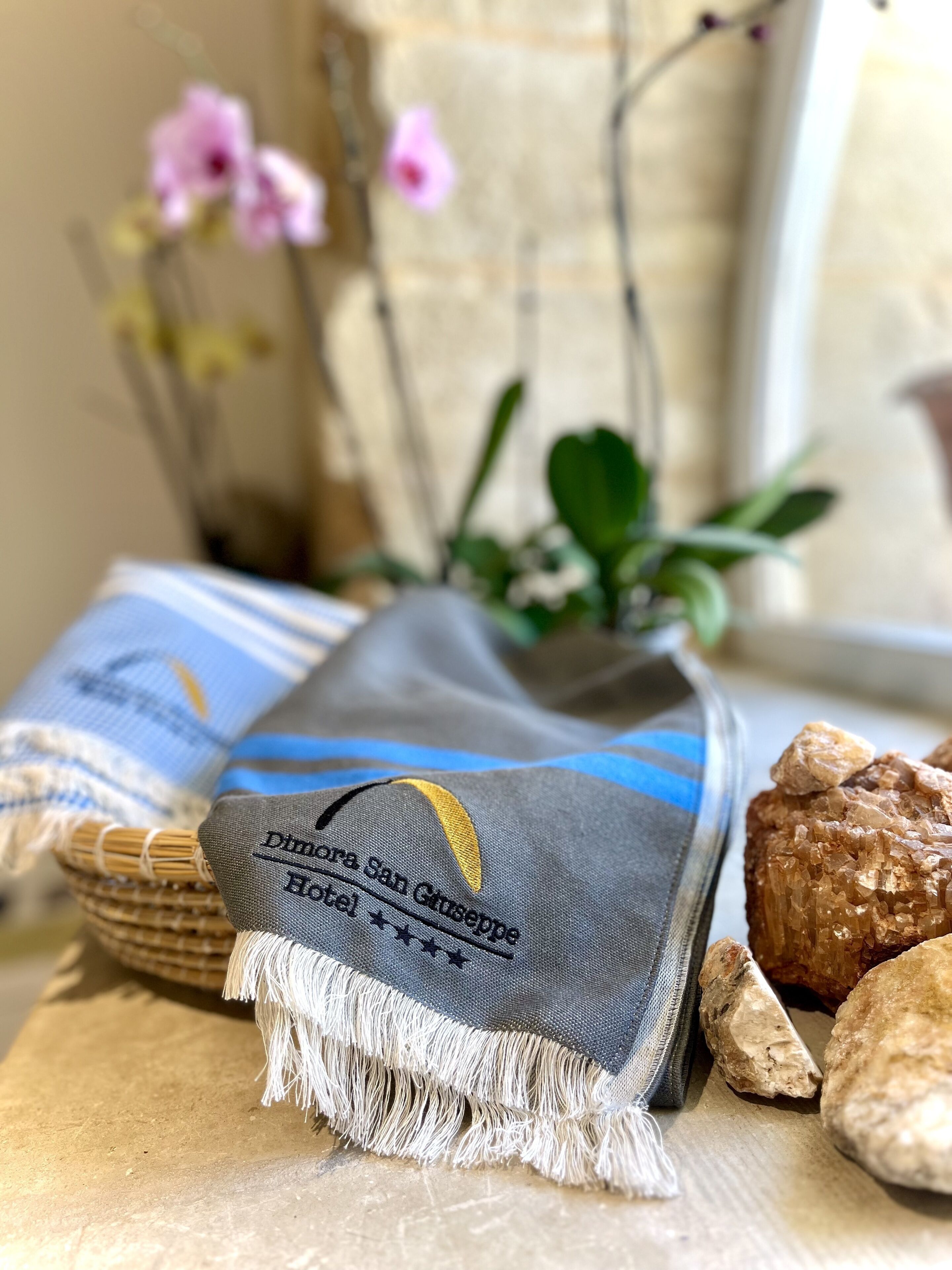 A woven fabric with embroidered text, a woven basket, and a rock.