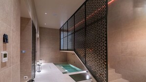 Un área de spa moderna con un jacuzzi, una escalera y un separador decorativo negro.