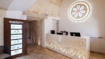 A reception area with a modern design, including a digital display board with hotel logos, a decorative ceiling light, and a reception desk.
