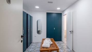 A hallway with a bench, a mirror, and a door with a towel on it.